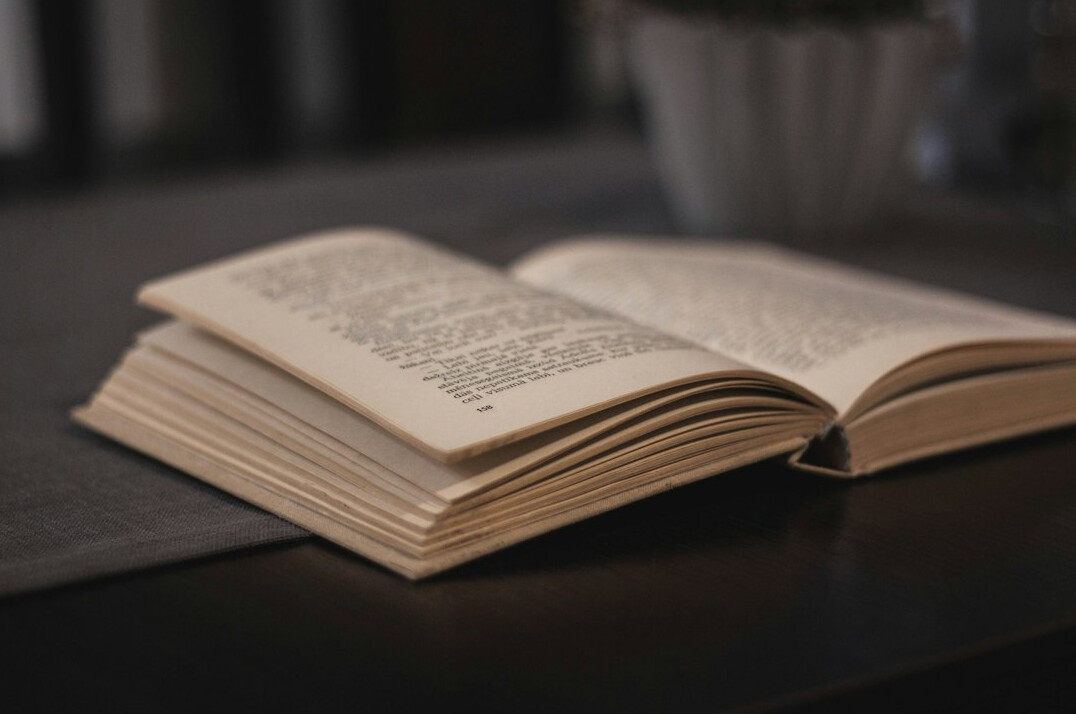Flat lay of open books and a notebook on a wooden desk